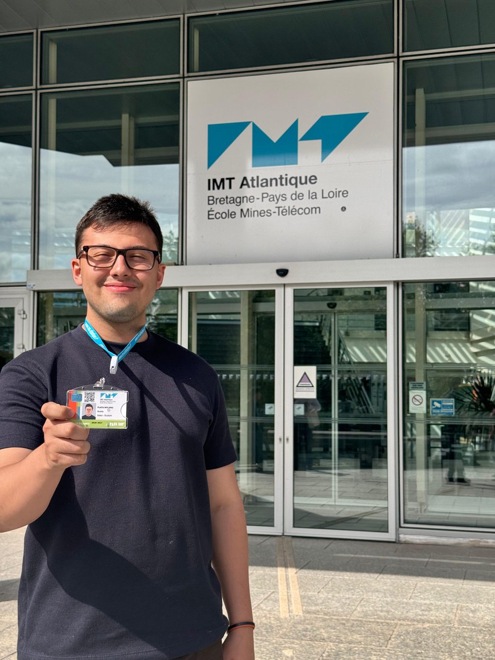 Nicolás devant l'entrée de l'IMT Atlantique à Nantes, avec sa carte d'étudiant